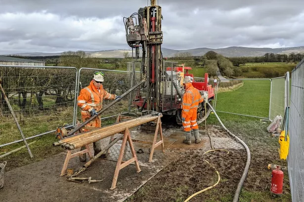 Two workers operating a drilling rig on temporary ground mats